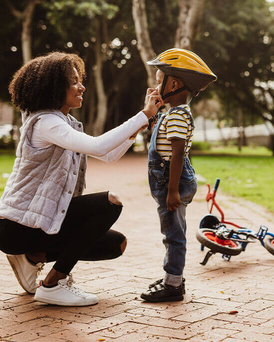 mother fixing her son's helmet for riding a bicycle 